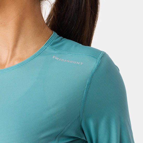 Detail van turquoise sportshirt met logo "SWEDEMOUNT" op de schouder.