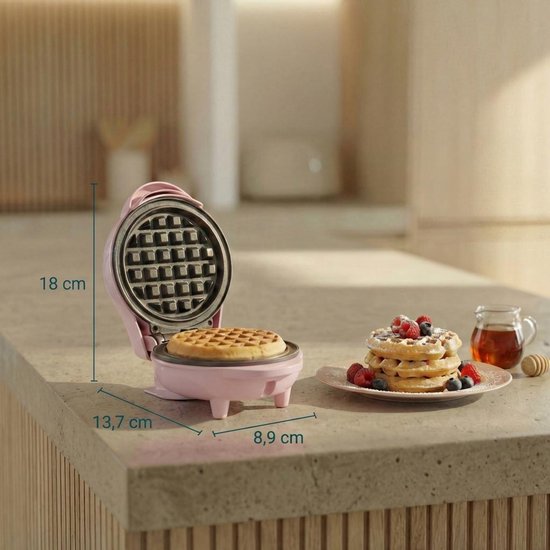 Roze wafelijzer open met versgebakken wafel, afmetingen 18x13,7x8,9 cm. Wafels met fruit ernaast.