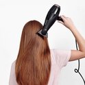 Vrouw met lang rood haar droogt haar haar met een zwarte BaByliss föhn.