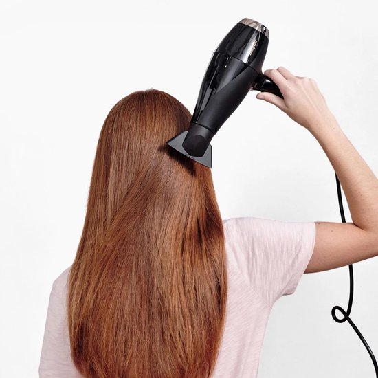Vrouw met lang rood haar droogt haar haar met een zwarte BaByliss föhn.