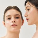 Close-up van twee modellen met het 'Ground Rice and Honey Glow Mask' aangebracht op hun gezicht.