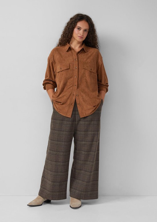 Model met bruine geruite culotte, bruine blouse en beige laarsjes.