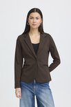 Vrouw, van voren gezien, met lange donkere haren, draagt bruine blazer, zwart topje, spijkerbroek.