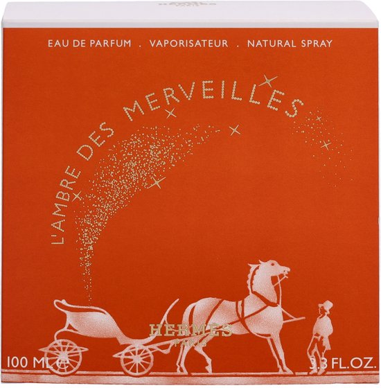 Oranje doosje voor "L'Ambre des Merveilles Eau de Parfum", met een gouden karos en paard, sprankelende sterren en "100 ML".