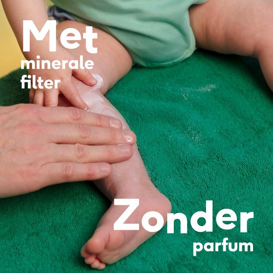 Babybeen dat ingesmeerd wordt met zonnebrandcrème door een hand.