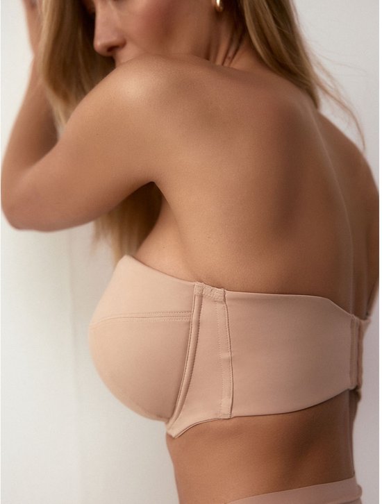 Zijaanzicht van een model dat een beige strapless bh draagt. De naden van de cup zijn zichtbaar.
