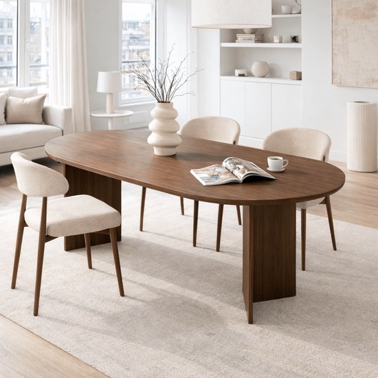 Ovale eettafel in walnoothout met een tijdschrift en kopje koffie erop.
