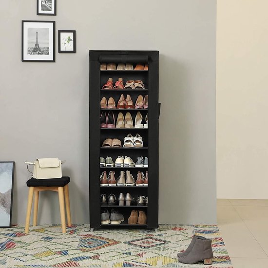 Zwarte schoenenkast met 10 etages, gevuld met schoenen. In een kamer met een kleed en een stoel.