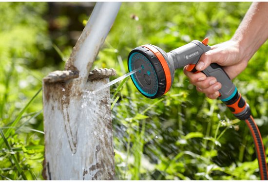 Grijze GARDENA spuit met oranje accenten sproeit water op een schop.