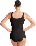 Achterkant van een vrouw in een zwarte singlet, staand met handen op de heupen.