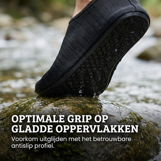 Voet in zwarte waterschoen met antislipzool op natte steen, voor optimale grip.