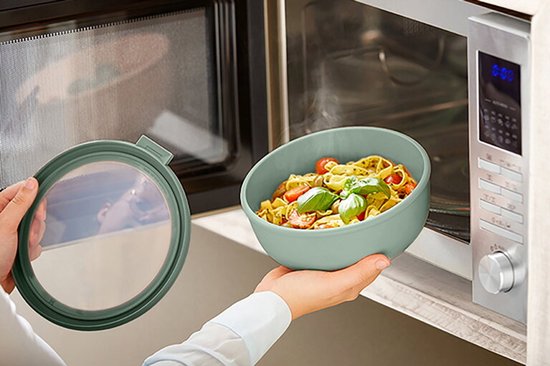 Une main retire un bol Mepal Cirqula vert pâle avec des pâtes du micro-ondes.