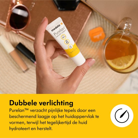 Een hand houdt een kleine tube Medela Purelan Lanolin cream vast, met een kop thee en zonnebril op de achtergrond.