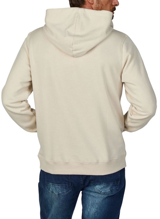 Achteraanzicht van een man die een beige hoodie draagt met de handen in de zakken.