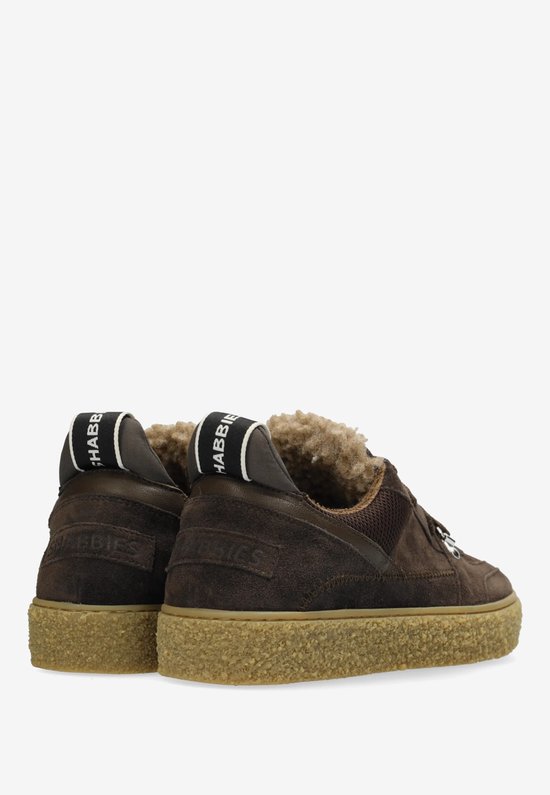 Achterkant van donkerbruine suède sneakers met crèmekleurige zool en teddy voering. Zwarte bandjes met "SHABBBIES" logo op de hiel.