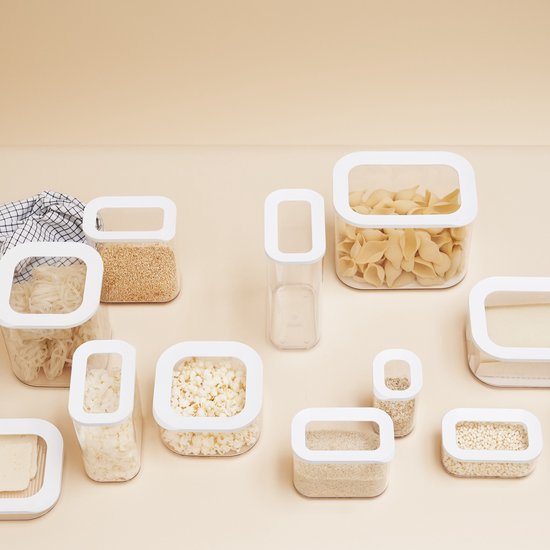 Un ensemble de boîtes de conservation Modula Mepal sur fond uni. Certaines boîtes contiennent du riz, des nouilles, du pop-corn et des graines de sésame.
