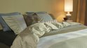 Un lit fait avec une housse de couette verte à rayures et plusieurs coussins.