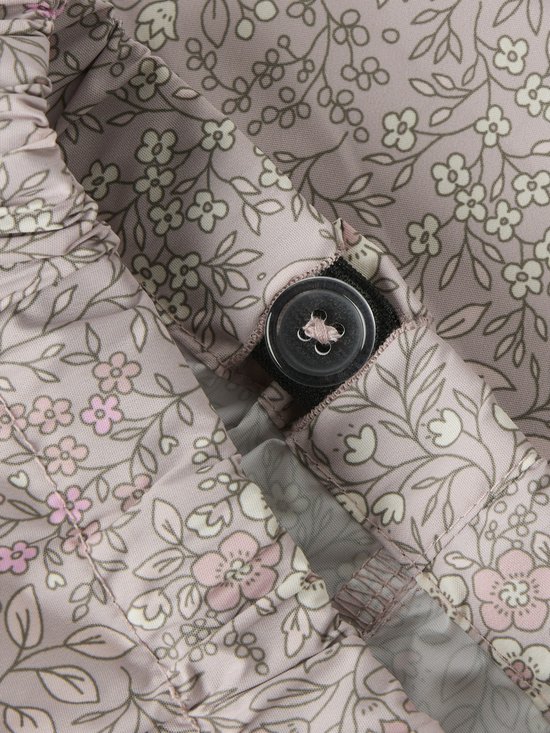 Roze regenbroek met een witte en lichtroze bloemenprint en een knoopsluiting.