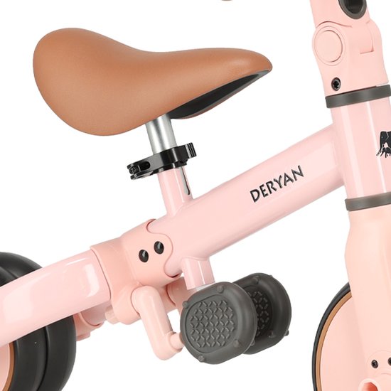 Detailopname van het bruine zadel en de pedalen van de roze Deryan loopfiets.