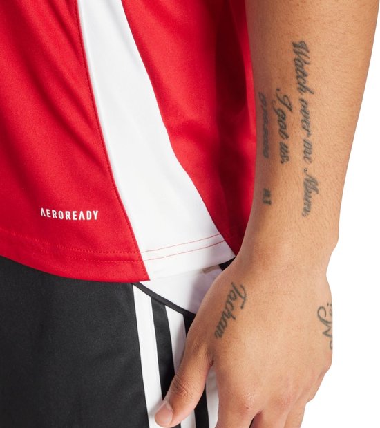Rood sportshirt met witte accenten aan de zijkant en AEROREADY logo. Close-up van de arm.