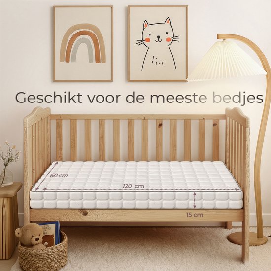 Een 60x120 cm babymatras van 15 cm dik in een houten ledikant, naast een nachtkastje met een teddybeer.