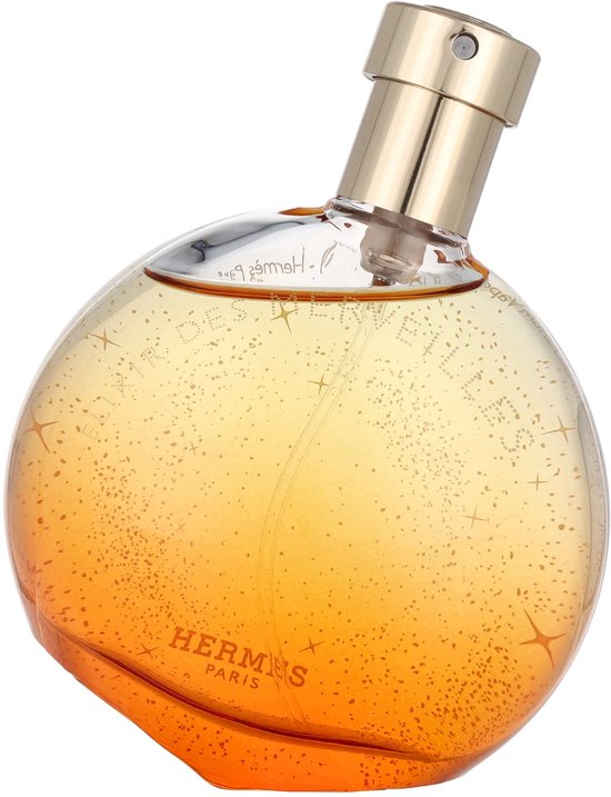 Ronde, oranje Elixir des Merveilles eau de parfum flacon met gouden dop. De flacon is bezaaid met gouden glitters.