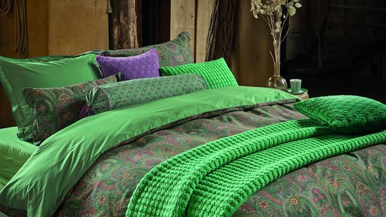 Groen bed met diverse kussens en een dekbedovertrek met paisley print.
