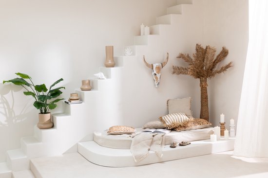 Bohemien loungehoek met een kunstpalmbomen decoratie, kussens en een koeienkop.