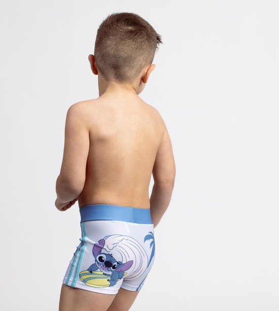 Jongen van achteren, draagt een witte zwembroek met Stitch op een surfplank.