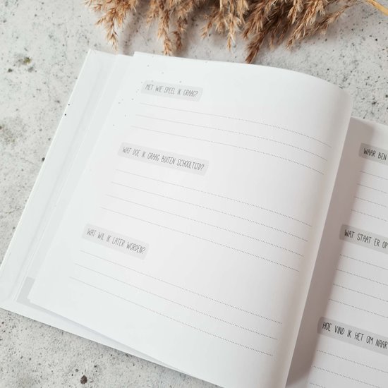Open invulboek met vragen over school: 'Met wie speel ik graag?', 'Wat doe ik graag buiten schooltijd?', 'Wat wil ik later worden?'.