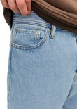 Close-up van de voorkant van een lichtblauwe jeans met zakken en knopen.