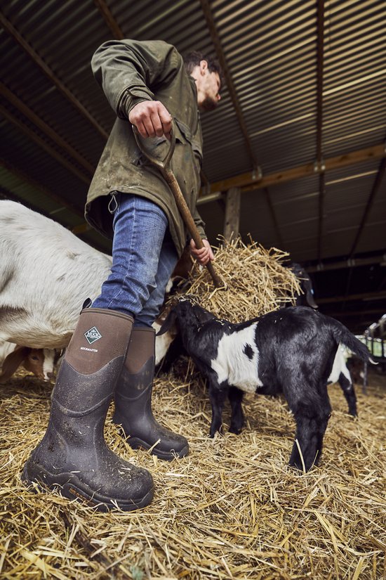 Laarzen van een boer in een stal, met geiten en stro. De laarzen zijn donkerbruin met een bruine stoffen schacht.