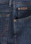 Close-up van de zak van een donkerblauwe Wrangler jeans met koperen knopen en bruin merklabel.