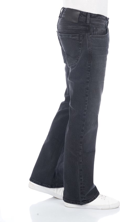 Zijaanzicht van een man met donkergrijze bootcut jeans, gedragen met witte sneakers.
