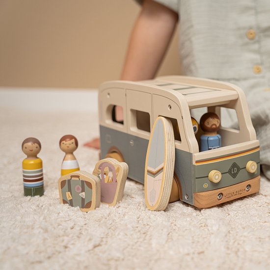 Houten camper met poppetjes, surfplank en koffers op een zachte kleed. Een kind speelt ermee.
