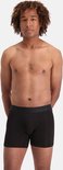Man met krullend haar draagt zwarte boxershorts met zwarte tailleband.