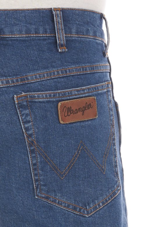 Detail van een blauwe Wrangler jeans, met bruin leren label op de achterkant.