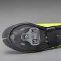 Zool van een neongele fietsoverschoen met fietsschoenplaatjes, klittenbandsluiting en reflecterende details.