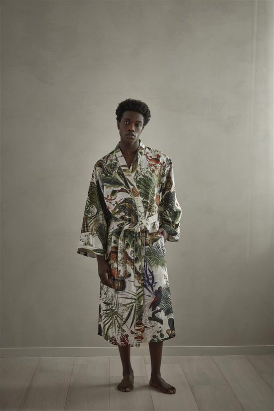 Model staat recht, gekleed in een lichte badjas met veelkleurige jungleprint van bladeren en dieren.