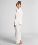 Model met knotje op de rug gezien in een witte pyjamaset.
