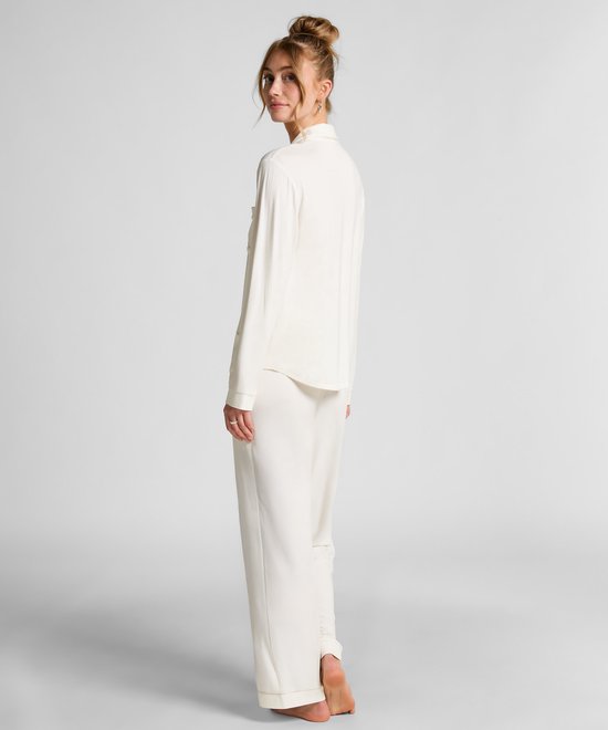 Model met knotje op de rug gezien in een witte pyjamaset.