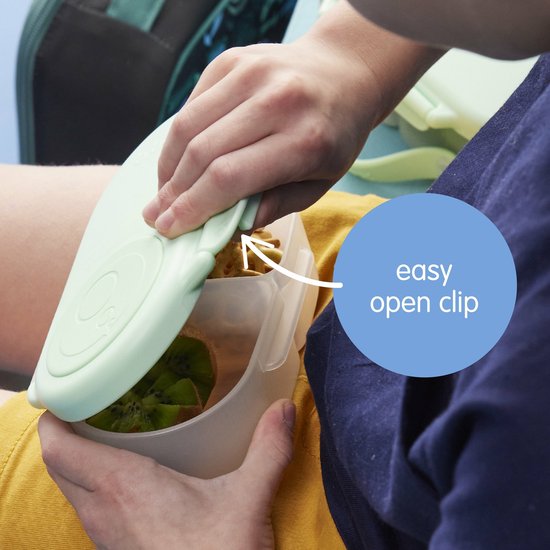 Mains d'enfant ouvrant une boîte à goûter b.box vert pâle avec un "clip d'ouverture facile".