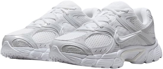 Een paar witte Nike sneakers, zijaanzicht, met Nike logo en mesh delen.