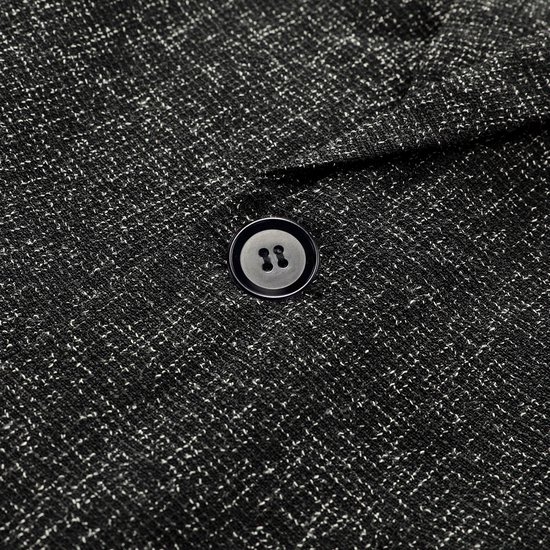 Close-up van de sluiting met één knoop van een donkergrijs jewelsteek blazer, met een lichte voering aan de binnenkant.