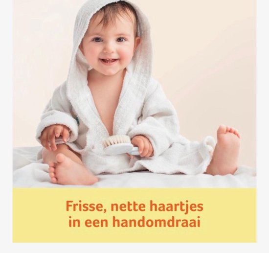 Baby in wit badjasje met capuchon, lacht en houdt een borstel vast.