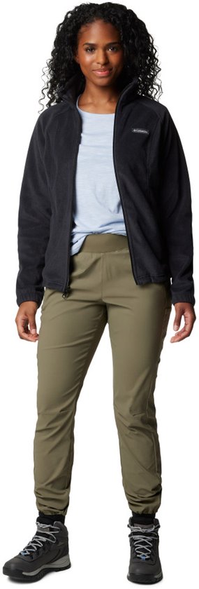 Model draagt een zwarte Columbia fleece trui met rits, lichtblauwe top en olijfgroene broek.