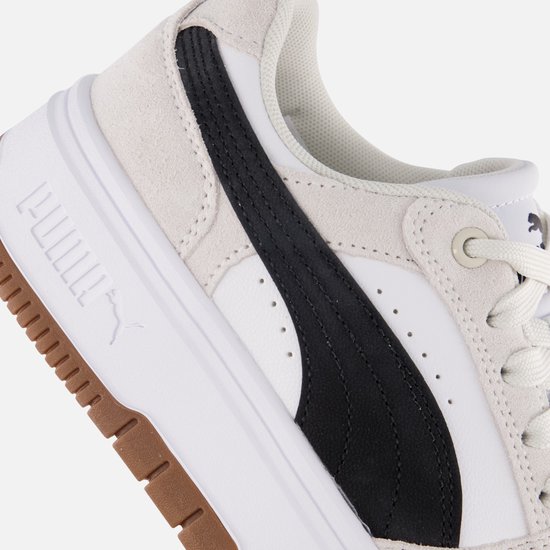Close-up van de zijkant van een witte Puma sneaker met zwarte streep en bruine zool.