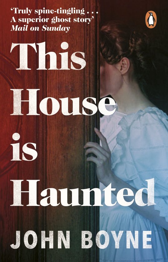 Boekomslag: Vrouw in wit, kijkend over schouder, deuren, titel "This House is Haunted", auteur "JOHN BOYNE".