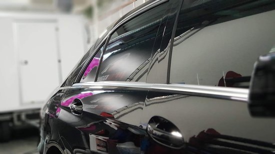 Zij-aanzicht van zwarte auto met getinte ruiten.