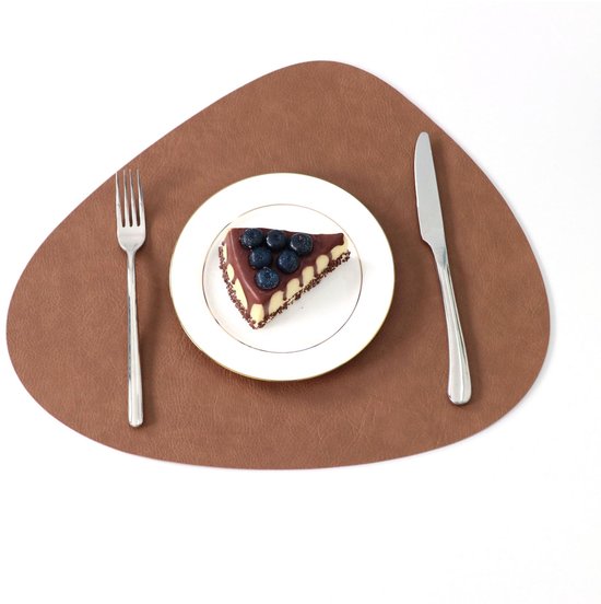 Tapis de table brun avec une part de gâteau aux myrtilles, à côté de couverts.